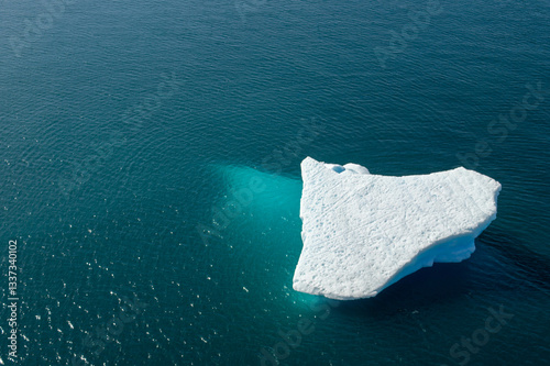 Drone photography of a white iceberg over blue turquoise water