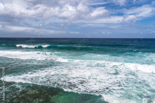 Turquoise ocean waves breaking on tropical shoreline. Coastal view of crystal clear ocean waves with white foam.Pristine seascape