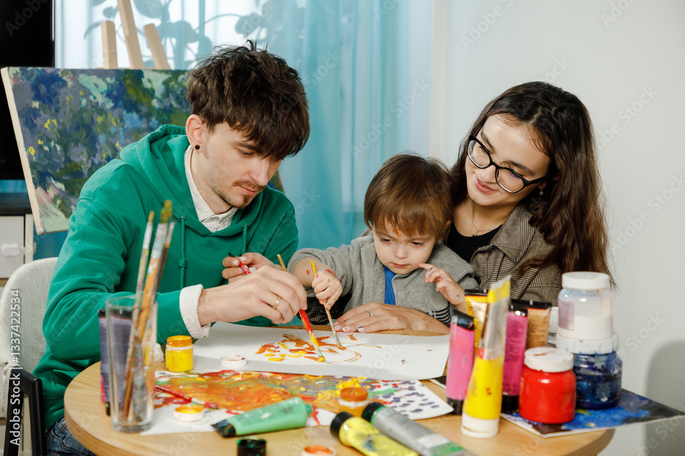 Fototapeta premium Young family with their son painting and having fun in the room