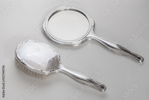 An antique hand mirror featuring a ornate silver handle and a round reflective surface. The mirror shows signs of aging and wear, adding to its vintage charm, mirror on white background