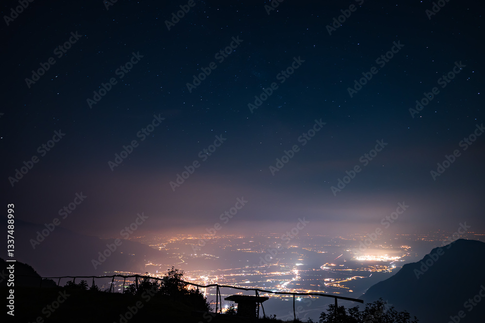 panoramica notturna dall'alto con cielo stellato sul territorio di Gemona del Friuli, nel Friuli Venezia Giulia centro-settentrionale, velato da una leggera nebbia, in estate