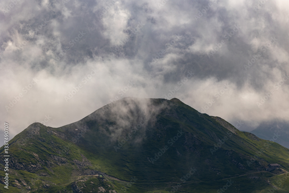 dettaglio di una cima erbosa di una montagna nell'Italia centro-settentrionale, di giorno, in estate, coperta ed avvolta da nuvole grigie