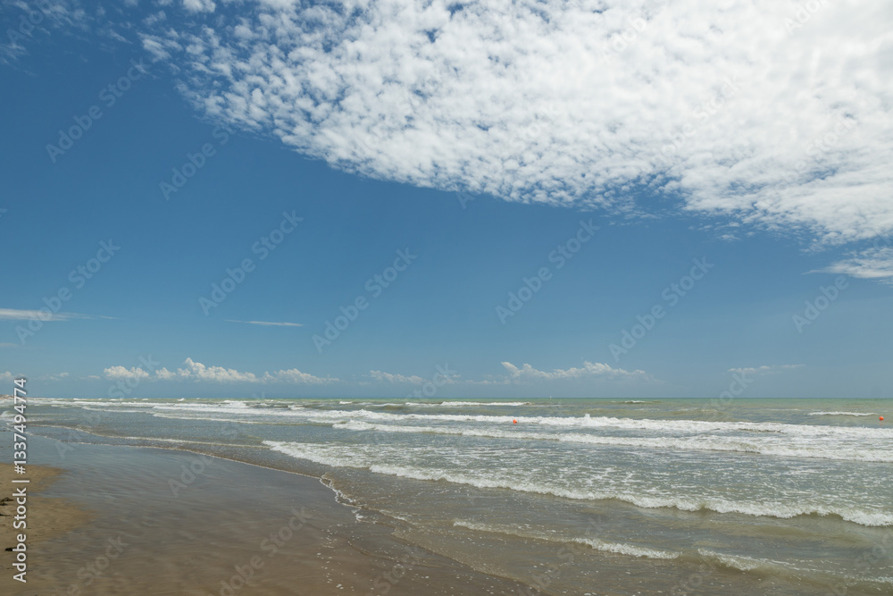 vista panoramica che si estende dalla vicina costa del Veneto e si affaccia sul mare Adriatico, guardando verso il lontano orizzonte, con mare mosso, di giorno, in estate e cielo sereno