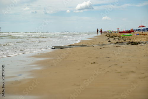 Obraz na płótnie coppia lontana, girata di spalle ed irriconoscibile che cammina di giorno in riva al mare, tenendosi per mano, in estate w salonie