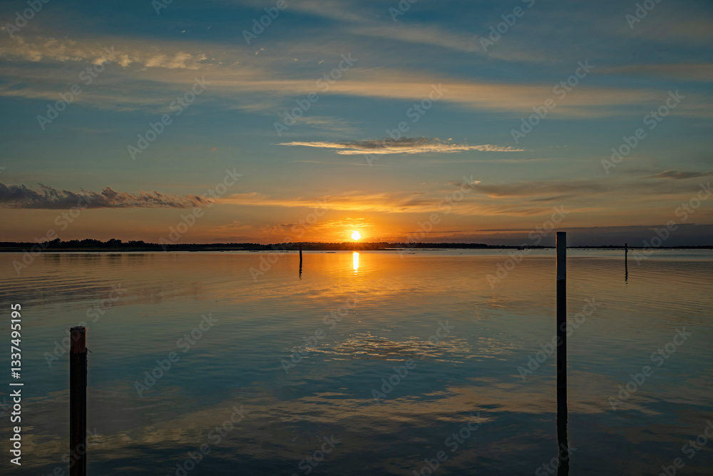 panoramica su un bellissimo tramonto su un'area naturale lagunare marina nel Veneto sud-orientale, con cielo leggermente nuvoloso e colori brillanti