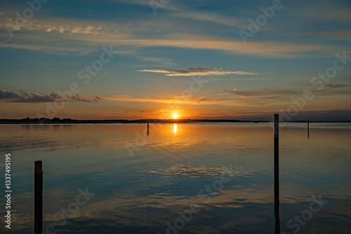 panoramica su un bellissimo tramonto su un'area naturale lagunare marina nel Veneto sud-orientale, con cielo leggermente nuvoloso e colori brillanti