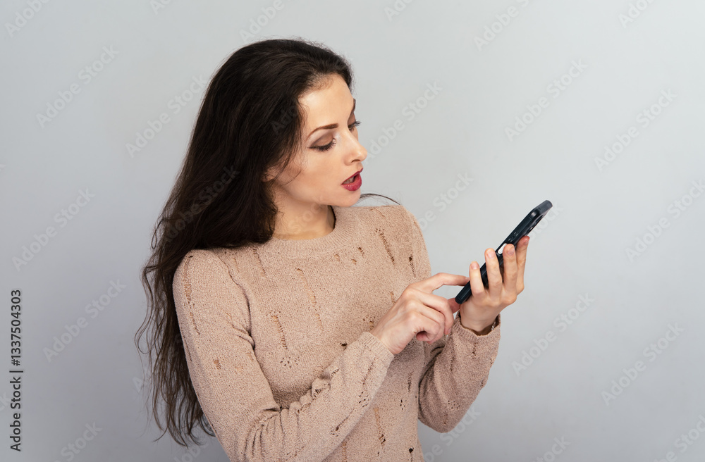 Beautiful woman holds mobile phone for online work, chating , texting, typing finger a text on the screen In studio light. Face people head portrait. Closeup Beautiful woman holds mobile phone for online work, chating , texting, typing finger a text on the screen In studio light. Face people head portrait. Closeup