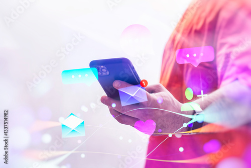 Fotografija A man wearing a orange vest holds a smartphone displaying chat and email notifications, surrounded by vibrant digital icons