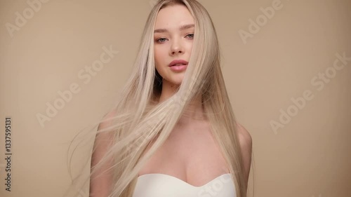 Beautiful woman with blond healthy hair on beige background. Hair beauty.