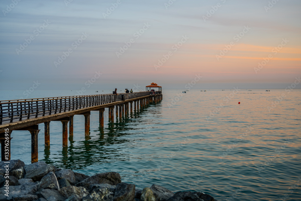 Scenic Wooden Pier Extending Over the Calm Sea at Sunset in Kuwait Scenic Wooden Pier Extending Over the Calm Sea at Sunset in Kuwait
