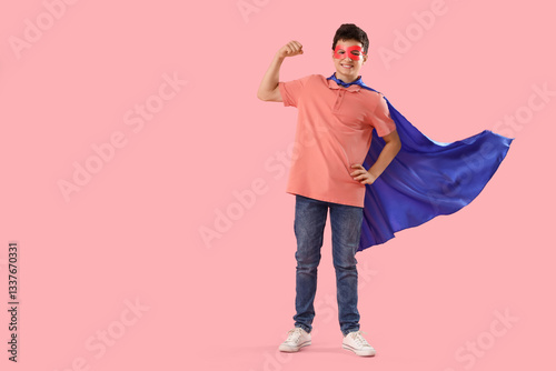 Teenage boy dressed as superhero on pink background
