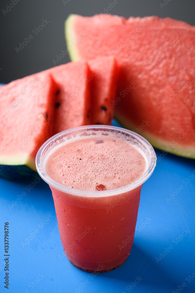 Watermelon smoothie in plastic cup on blue background, closeup.
Watermelon smoothie in plastic cup on blue background, closeup.