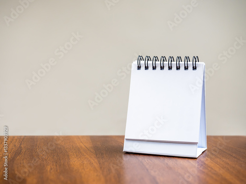 Blank page of desk spiral calendar for organizer concept to plan and reminder, standing on wooden table and grey background. Mock up small table calendar paper, front view, template photo for design.