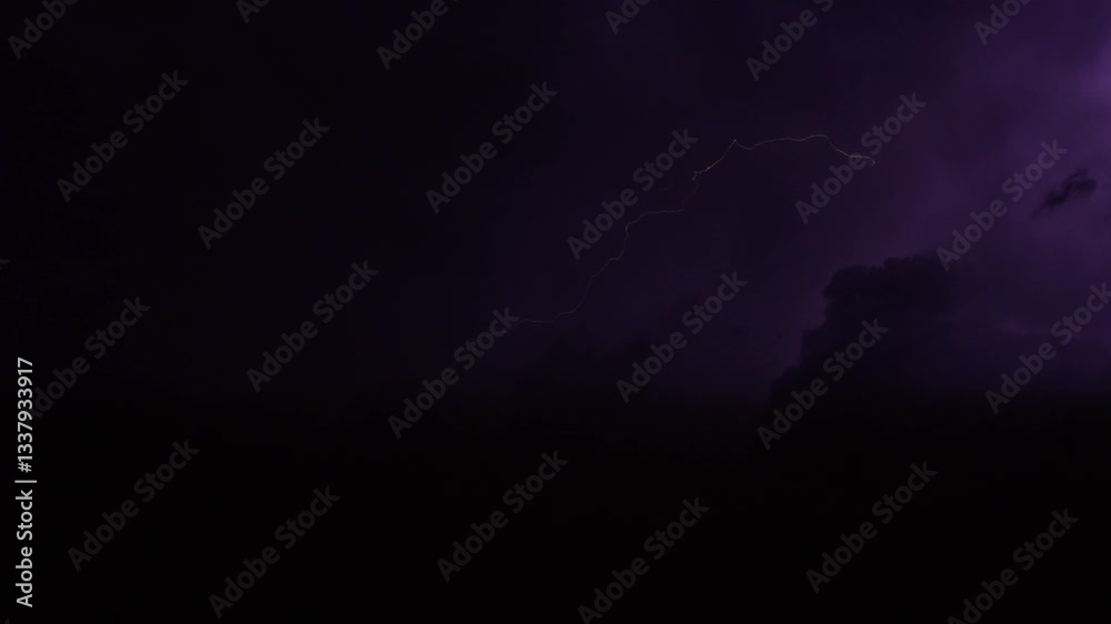 Stormy night sky with fast-moving clouds, sporadically lit by flashes of lightning