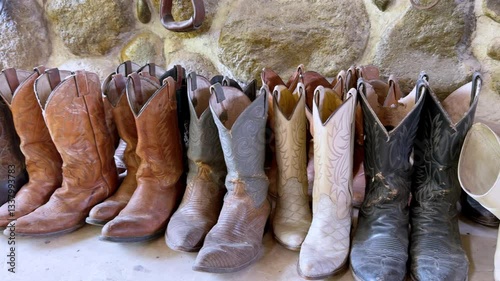 Rustic cowboy boots lined up against a stone wall in a western style setting