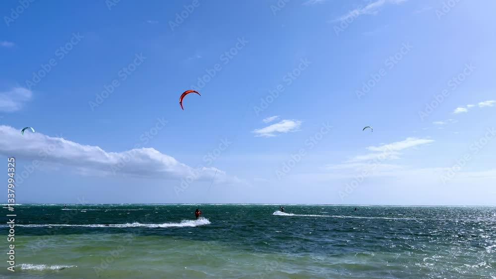 Kite surfers riding the waves in the ocean on a sunny and windy day Kite surfers riding the waves in the ocean on a sunny and windy day