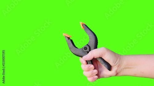 Animation human hand squeeze plastic spring clamp, commonly used in DIY projects, crafting, and woodworking isolated on green screen background. 4K video.