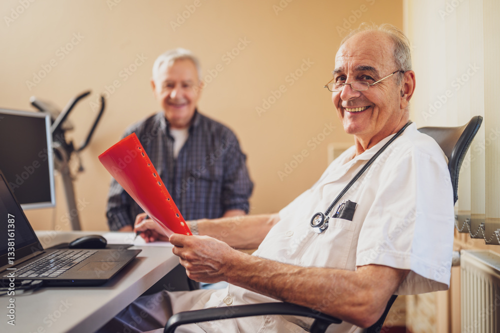 Obraz premium Elderly patient is having exam at cardiologist. Doctor is looking at his medical files. Happy doctor and patient smiling.