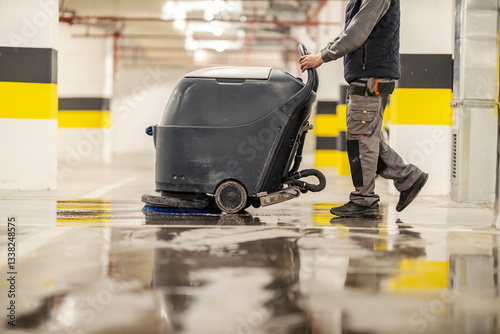 Side view of an unrecognizable worker washing public garage with washing machine.