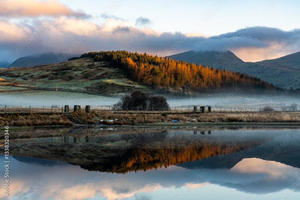 Fototapeta premium Reflections of Snowdonia mountains during golden hour in Llyn y Gadair