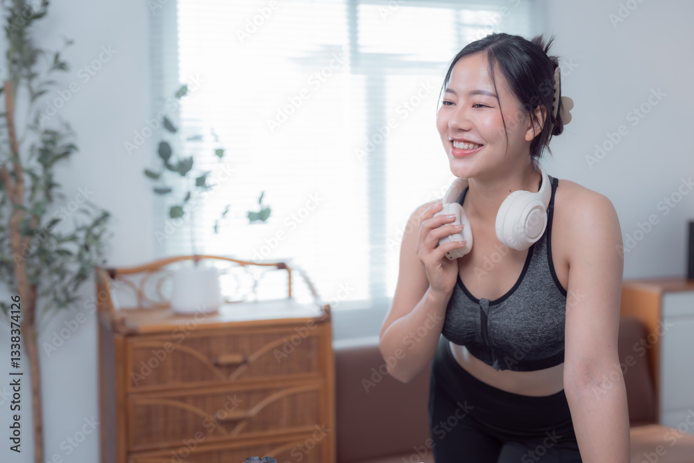 Happy sportswoman enjoying a break during a home workout, listening to music with wireless headphones and smiling, embracing a vibrant and healthy lifestyle filled with energy and motivation Happy sportswoman enjoying a break during a home workout, listening to music with wireless headphones and smiling, embracing a vibrant and healthy lifestyle filled with energy and motivation