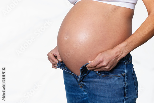 Obraz na płótnie Close-up view of a pregnant woman with a big belly trying to put on a trouser w salonie