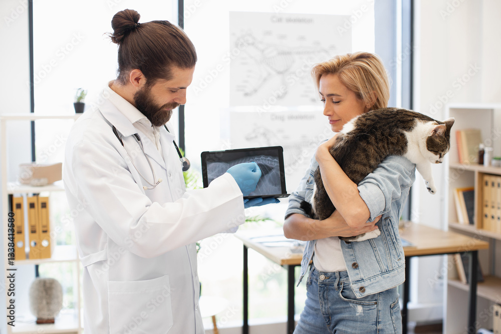 Obraz premium Male veterinarian showing x-ray results to female cat owner holding her pet cat. Medical consultation regarding pet health in clinic environment with caring professional.