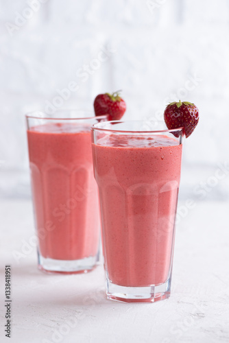 Strawberry cold cocktail, smoothie from strawberries, coconut cream, green buckwheat in two glasses. Lactose and sugar free. Vertical orientation.