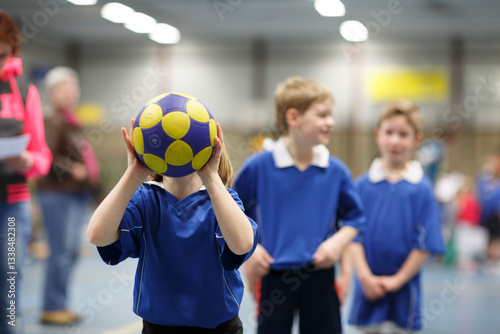 Fototapeta Naklejka Na Ścianę i Meble -  Kids participate in a fun indoor handball practice session at a local sports facility in early spring