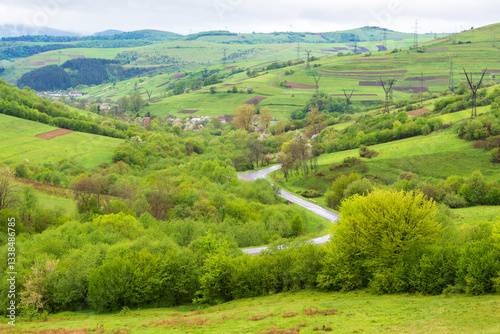travel landscape, with road through valley. green nature scenery in spring for tourism. beautiful rural background view from the hill with forest. outdoor adventure in the rain