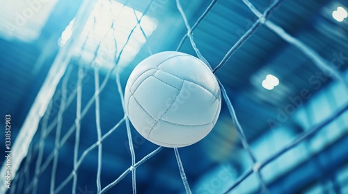 Close-up low angle view of white leather volleyball flying above net during intense indoor volleyball match in stadium arena with dramatic lighting and competitive atmosphere




