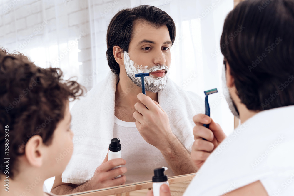 Little son looks like father shaves beard with razor. Little son looks like father shaves beard with razor.