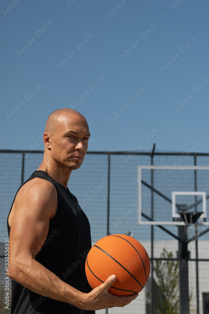 Basketball player hold orange basketball ball on sports field. Basketball coach. Summer. Outdoors