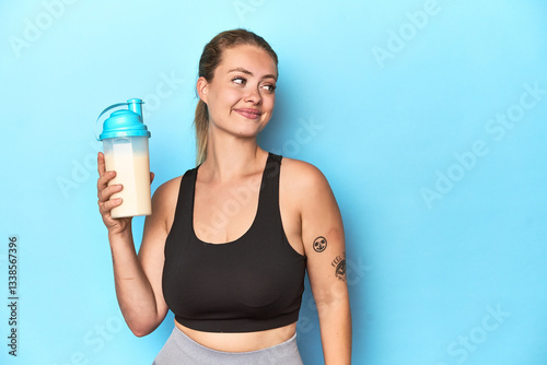 Photography Sporty blonde with a protein shake in a studio dreaming of achieving goals and p