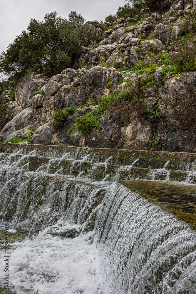 Waterfall cascading down rocky terrain in natural landscape