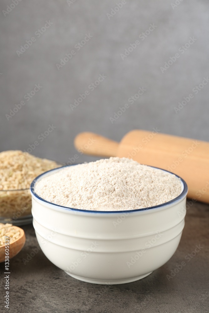 Brown rice flour on grey table, closeup. Space for text Brown rice flour on grey table, closeup. Space for text