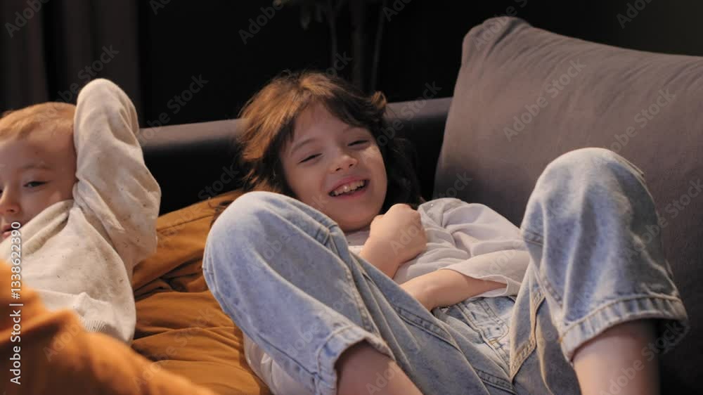 Mother tickling and playing with daughter and son on sofa