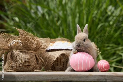 Young rabbit with pink easter egg and festive cake