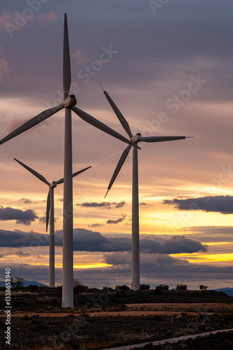 Wind farm at twilight with multiple turbines, blending industrial infrastructure with the serene beauty of a Zaragoza sunset, illustrating renewable energy expansion. photo