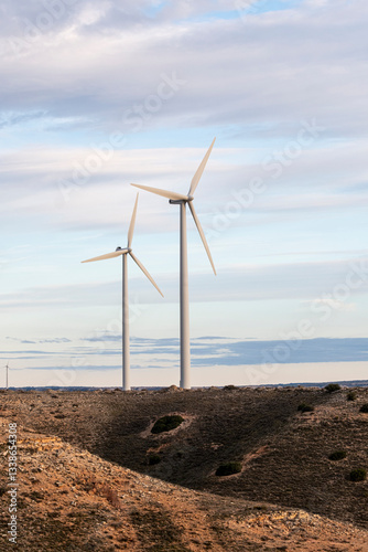 Minimalist view of wind turbines standing on an open landscape in Zaragoza, emphasizing sustainable energy solutions under a soft, cloudy sky.