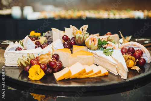 Cheese plate and fruits. Serving on a black platter