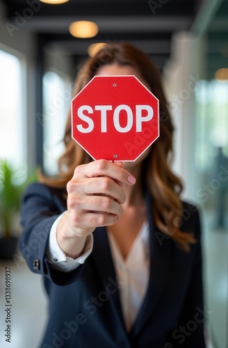 Businesswoman holding stop sign in office corridor