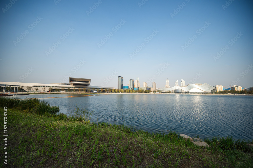 Naklejka premium Serene Urban Waterfront View with Modern Architecture and City Skyline