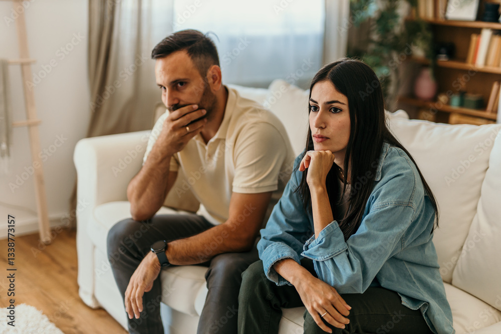 Worried couple sitting on sofa thinking about problems in relationship Worried couple sitting on sofa thinking about problems in relationship