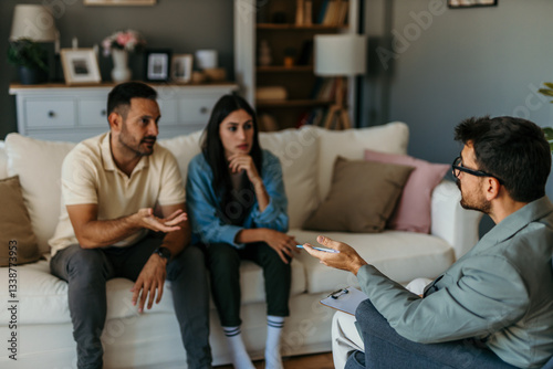 Obraz na płótnie Couple arguing during therapy session with psychologist taking notes