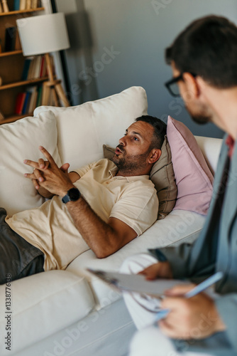Patient talking about problems while lying on sofa to psychologist taking notes