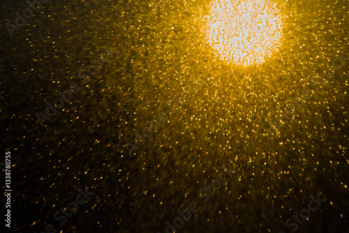 Blurred bokeh light sparkle on golden black background