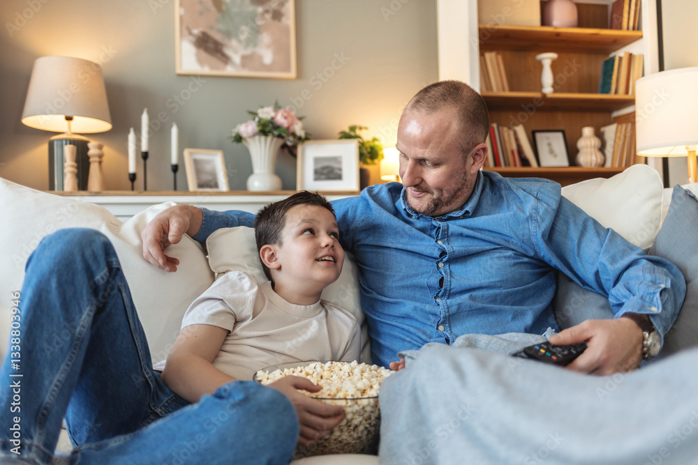 Obraz premium Father and son caucasian watch football match and cheer at home noisy, excited, happy. Father and son spending time near tv with bucket of popcorn at home.
