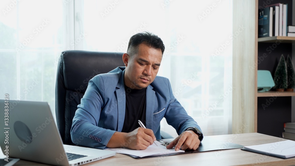 Young businessman working with document and laptop on desk at office Young businessman working with document and laptop on desk at office