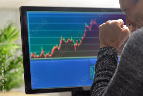 Excited male beginner trader analyzing stockmarket using computer. Man at home, back view, trading stocks on monitor. Beginner in stock exchange business, part-time job